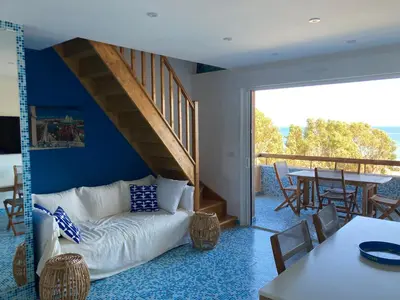 a living room with a white couch and a table at Duplex terrasse vue mer in Pisinale