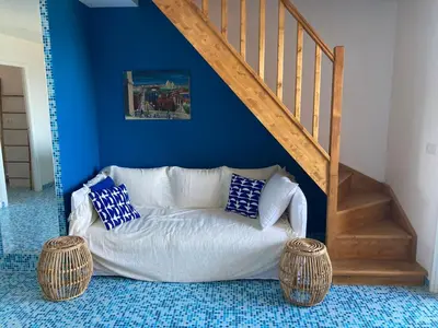 a white couch sitting under a staircase with blue walls at Duplex terrasse vue mer in Pisinale