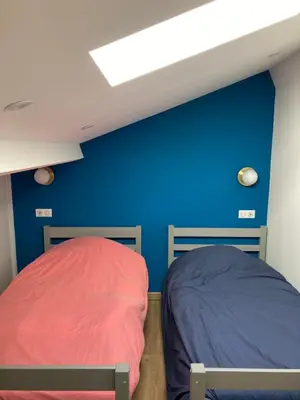 two beds in a room with a blue wall at Duplex terrasse vue mer in Pisinale