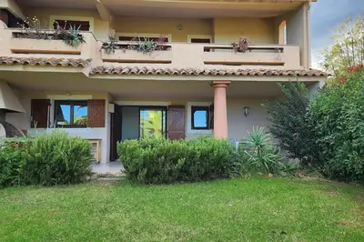 a house with a balcony and a grass yard at Mini villa Favone in Conca