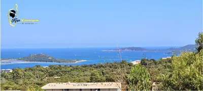 a view of the ocean from a hill with a building at Paradiso T3 vue Mer Piscine Partagée in Porto-Vecchio