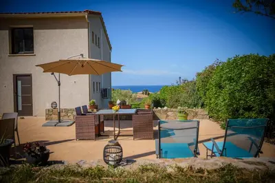a patio with a table and chairs and an umbrella at Casa Kallinina in Esigna