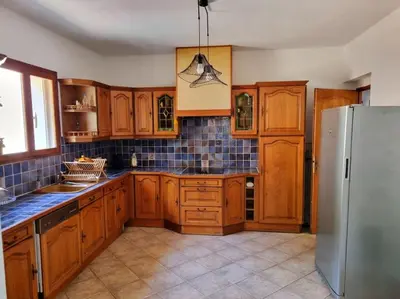 a kitchen with wooden cabinets and a stainless steel refrigerator at Maison agréable avec grands volumes in Levie