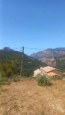 a field with a house and mountains in the background at A casa di Francesca in Marignana