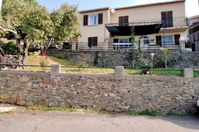 a stone retaining wall in front of a house at Maison de village corse in Campitello