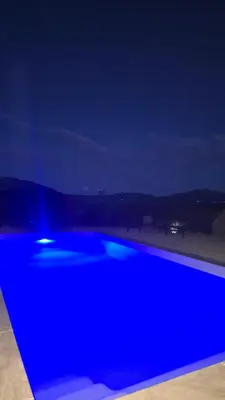 a blue swimming pool at night at Bas de villa avec piscine in Moltifao