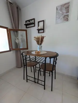 a small table with two chairs and a vase on it at La chambre de Ptitruc au coeur du maquis in Granace