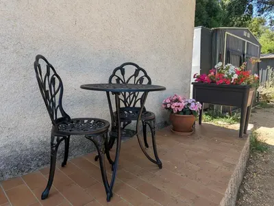 two chairs and a table on a patio with flowers at La chambre de Ptitruc au coeur du maquis in Granace