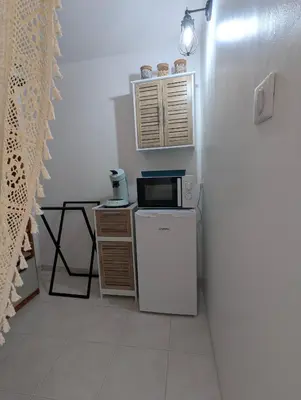 a small kitchen with a microwave and a refrigerator at La chambre de Ptitruc au coeur du maquis in Granace