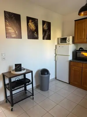 a kitchen with a white refrigerator and a table at Mini villa piscine et plage in Cervione