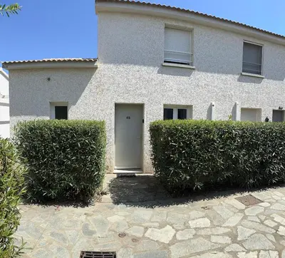 a building with a white door and some bushes at Mini villa piscine et plage in Cervione