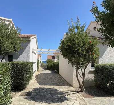 a walkway between two white houses with a tree at Mini villa piscine et plage in Cervione
