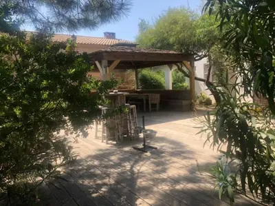 a patio with a wooden pergola and a table at Villa à Cala-Rossa,Porto-Vecchio proche des plages in Le Ranch