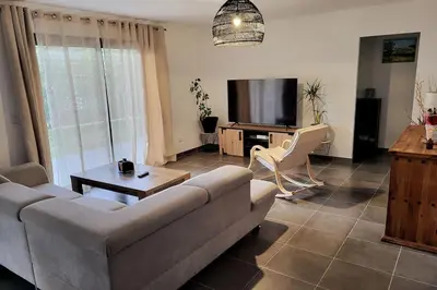 a living room with a couch and a tv at Charmante villa avec jardin in Prunete
