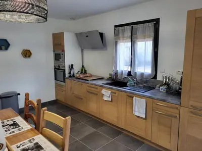 a kitchen with wooden cabinets and a table and a window at Charmante villa avec jardin in Prunete