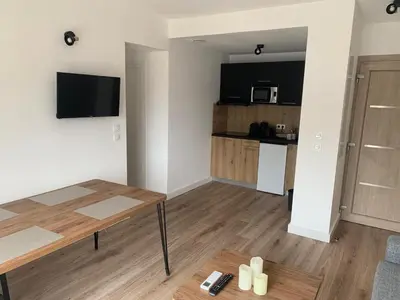 a living room with a table and a kitchen at Appartement en résidence privée in Le Ranch