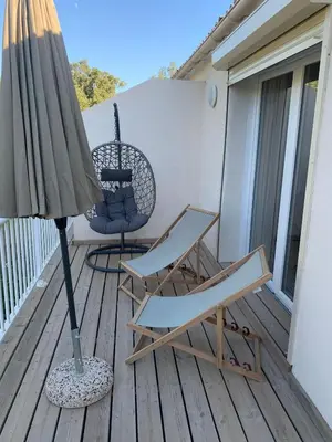 a patio with two chairs and an umbrella on a deck at Appartement en résidence privée in Le Ranch