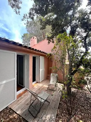 a wooden deck with two chairs on a house at Logement Mésange600m à pied de SantaGiulia Jacuzzi in Porto-Vecchio