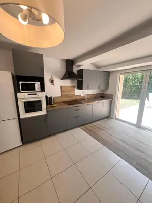 a kitchen with gray cabinets and a white tile floor at Logement Linotte, 600m à pied Santa Giulia Jacuzzi in Bocca del Oro