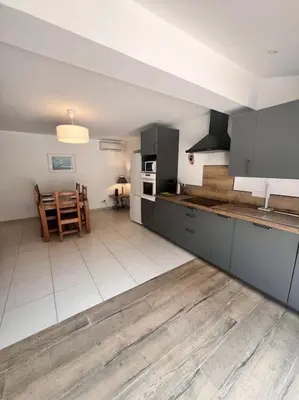 a kitchen with gray cabinets and a table in a room at Logement Linotte, 600m à pied Santa Giulia Jacuzzi in Bocca del Oro