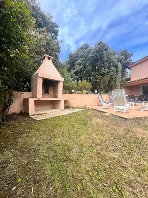 a backyard with a stone fireplace and two chairs at Logement Linotte, 600m à pied Santa Giulia Jacuzzi in Bocca del Oro