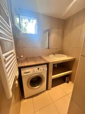 a small bathroom with a washing machine and a sink at Logement Linotte, 600m à pied Santa Giulia Jacuzzi in Bocca del Oro