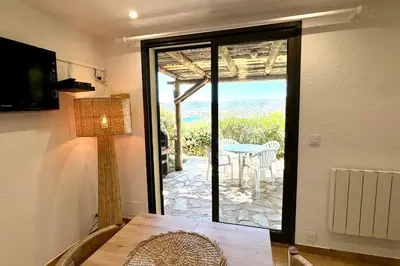 a room with a table and a view of a patio at Adorable duplex vue mer 5 min à pied de Santa Giulia in Porto-Vecchio