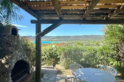 a table and chairs on a patio with a view of the ocean at Adorable duplex vue mer 5 min à pied de Santa Giulia in Porto-Vecchio