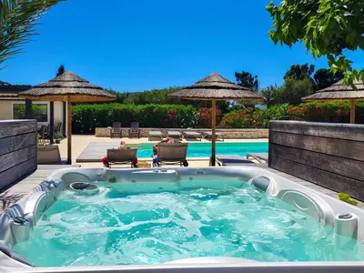 a hot tub on a patio next to a pool at Hôtel Padolo in Bonifacio