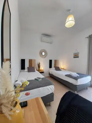 a hotel room with two beds and a table at Hôtel Padolo in Bonifacio