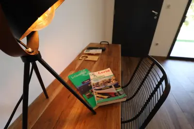 a table with a book on it next to a lamp at Hôtel Padolo in Bonifacio