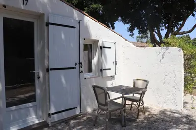 a table and chairs next to a white building at Hôtel Padolo in Bonifacio