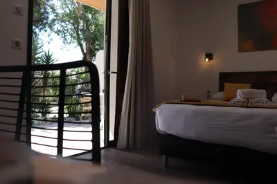a bedroom with a bed and a door to a balcony at Hôtel Padolo in Bonifacio