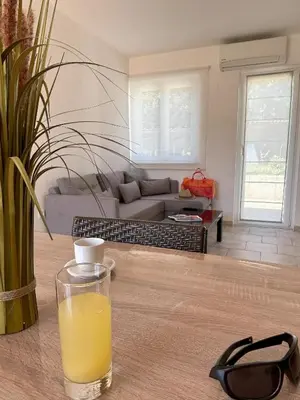 a glass of orange juice on a table in a living room at Hôtel Padolo in Bonifacio