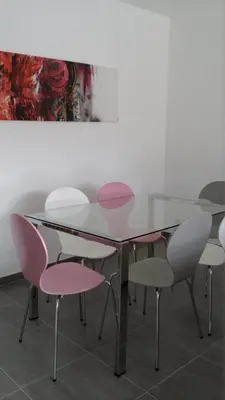 a dining room with a glass table and pink chairs at Résidence Isola Hotel in Borgo