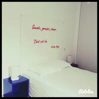 a bedroom with a bed with a writing on the wall at Résidence Isola Hotel in Borgo