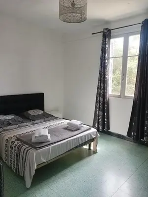 a bedroom with a bed and a large window at Chambres chez l'habitant in Ajaccio