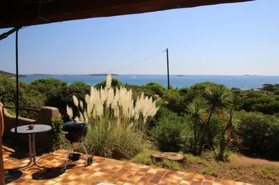 a patio with a grill and a view of the ocean at Villa Nitiola Plage de Palombaggia in Bocca del Oro
