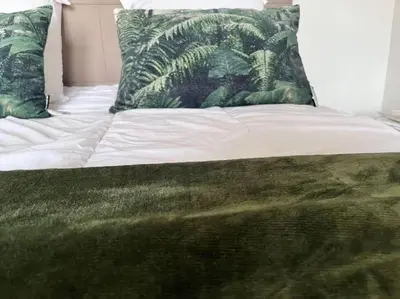 a bed with green and white sheets and pillows at CASA NINA FURIANI CORSE Appartement en résidence in Paterno