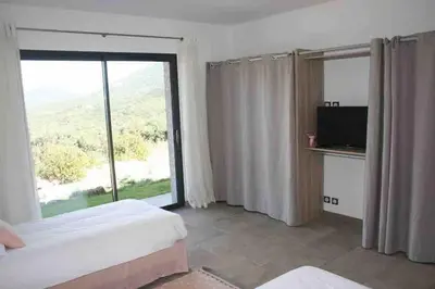 a bedroom with two beds and a large window at Villa avec vue panoramique mer et montagne in Portigliolo