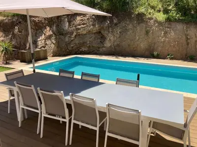 a table with chairs and an umbrella next to a swimming pool at Maison avec piscine, à proximité des plages in Porto-Vecchio