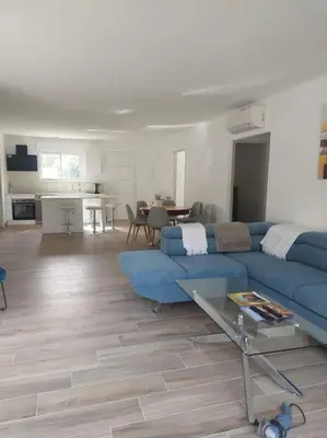 a living room with a blue couch and a kitchen at Maison avec piscine, à proximité des plages in Porto-Vecchio
