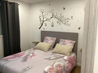 a bedroom with a bed with pink flowers on it at Appartement Bavella in Santa-Lucia-di-Moriani