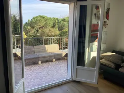 a sliding glass door leading to a patio with a bench at Appartement Bavella in Santa-Lucia-di-Moriani