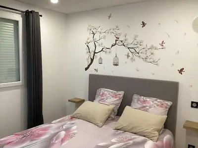 a bedroom with a bed with a tree on the wall at Appartement Bavella in Santa-Lucia-di-Moriani