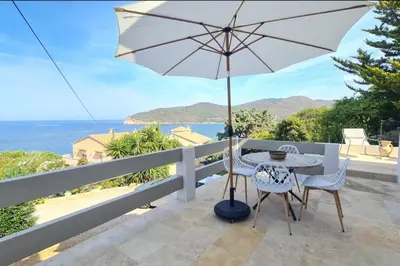 a table and chairs on a balcony with an umbrella at Apartment with balcony and 360 sea view in Villanova