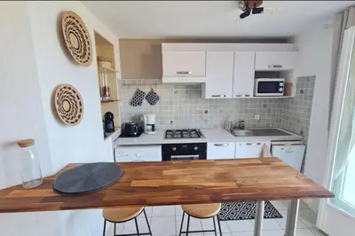 a kitchen with white cabinets and a wooden table at Apartment with balcony and 360 sea view in Villanova