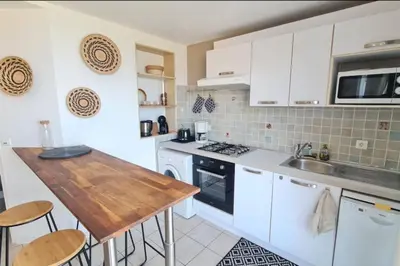 a kitchen with white cabinets and a wooden table at Apartment with balcony and 360 sea view in Villanova
