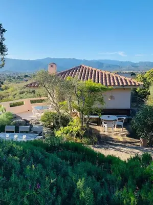 a house with a patio and a table and chairs at Sea view villa - Cala Rossa private park in Lecci