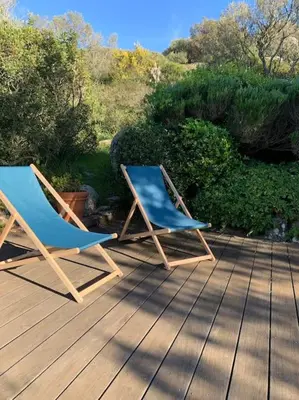 two chairs sitting on top of a wooden deck at Sea view villa - Cala Rossa private park in Lecci